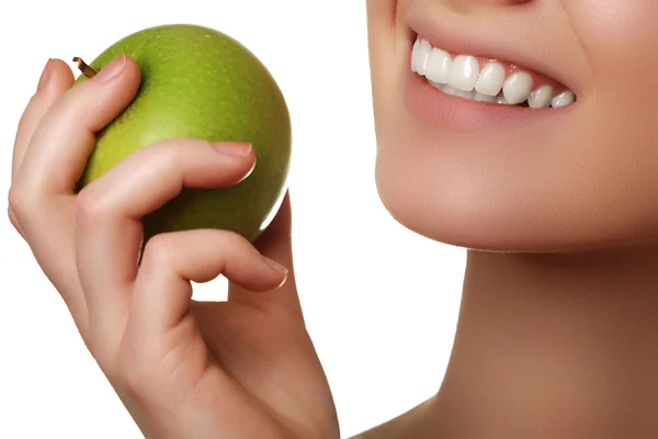 Primer plano de la cara de una mujer comiendo una manzana verde, aislada sobre fondo blanco. Hermosa cara de mujer adulta joven con piel limpia y fresca — Foto de Stock