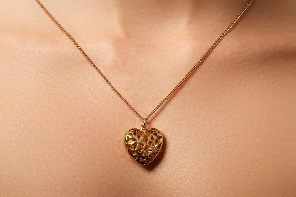 Colgante corazón dorado. Concepto de belleza y joyería. Mujer con colgante de oro brillante. Retrato de moda de hermosa mujer de lujo con joyas. Regalo para el día de San Valentín — Foto de Stock