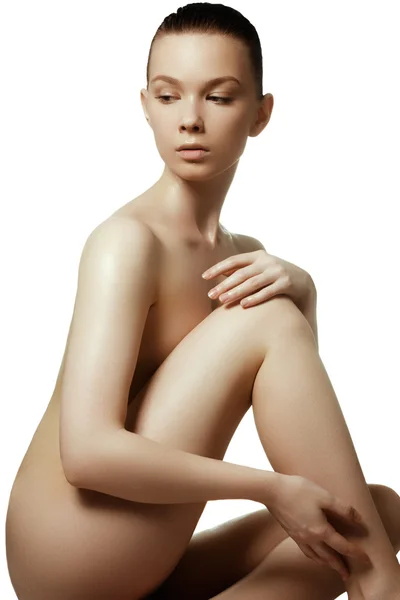 Obrázek zdravé nahé ženy s dokonalým tělem přes bílý. Krásná žena, sedící na podlaze dotek nohou — Stock fotografie