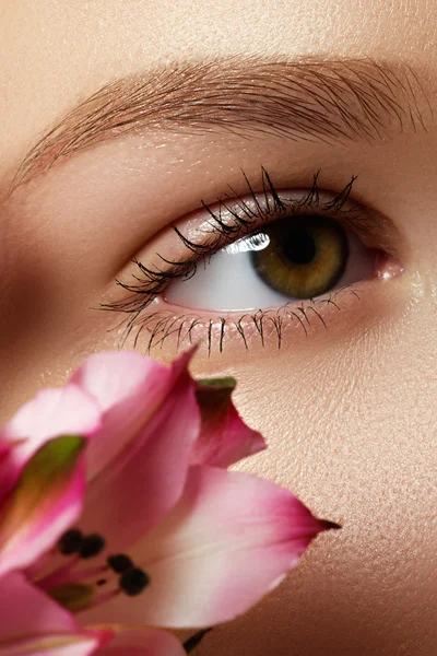 Hermosa modelo joven, hermoso ojo de mujer con flor rosa fresca, parte de la cabeza femenina, chica sexy con aspecto elegante, spa y fondo de belleza — Foto de Stock