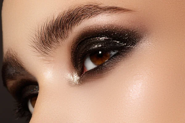 Elegancia primer plano de ojo femenino con maquillaje ahumado marrón oscuro clásico. Una foto macro de la cara de una mujer. Belleza, cosmética y maquillaje — Foto de Stock