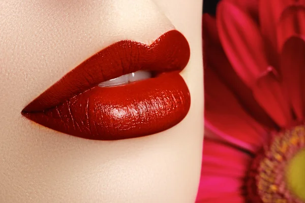 Primeros planos hermosos labios femeninos con maquillaje rojo brillante. Piel limpia perfecta, maquillaje de labios sexy. Hermoso retrato de spa con tierna flor roja. Spa y cosméticos — Foto de Stock