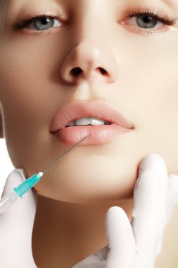 Genç kadın kozmetik enjeksiyon getting portresi. Tatlı güzel kadının yüzüne enjeksiyon alır. Dolgu enjeksiyonları. Dudak büyütme. Güzel mükemmel dudaklar