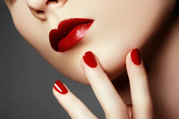 Skönhet modell. Välklippta hand med röda naglar. Röda läppar och naglar. Vacker kvinna med lyxiga smink och perfekt manikyr. Makeup koncept — Stockfoto