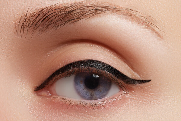 Beautiful model applying eyeliner closeup on eye