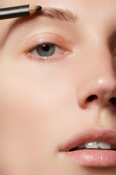 Визажист наносит макияж брови. Красивое женское лицо. Идеальный макияж
