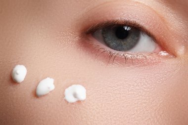 Portrait of young woman with fresh clean face with points of moisturizing  cream under the eye