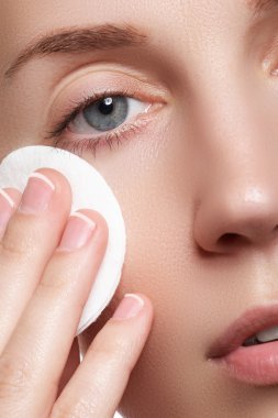 Mutlu portre güzel genç kadın temizlik cilt tarafından pamuk yastık, beyaz arka plan üzerinde gülümseyen. Kozmetik ve sağlık