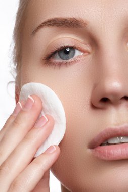 Mutlu portre güzel genç kadın temizlik cilt tarafından pamuk yastık, beyaz arka plan üzerinde gülümseyen. Kozmetik ve sağlık