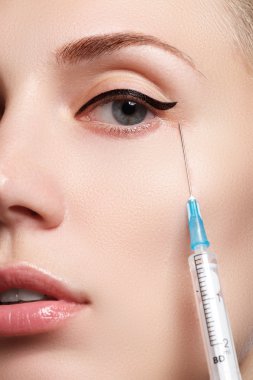 Güzel kadın closeup enjeksiyon alır. Dolgun dudaklar. Güzel bir yüzü ve şırınga (estetik cerrahi ve kozmetik enjeksiyon kavramı).