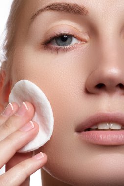 Mutlu portre güzel genç kadın temizlik cilt tarafından pamuk yastık, beyaz arka plan üzerinde gülümseyen. Kozmetik ve sağlık