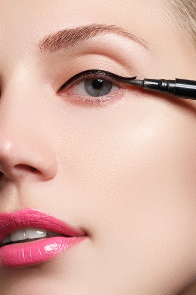 Hermosa mujer con brillante maquillaje ojo con maquillaje negro sexy. Forma de flecha de moda. Maquillaje elegante de la noche. Maquillaje belleza con cepillo delineador de ojos en cara de mujer bonita — Foto de Stock