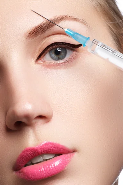 Güzel kadın closeup enjeksiyon alır. Dolgun dudaklar. Güzel bir yüzü ve şırınga (estetik cerrahi ve kozmetik enjeksiyon kavramı).
