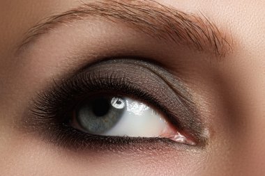 Macro shot of woman's beautiful eye with extremely long eyelashes. Sexy view, sensual look. Fashion smoky makeup.