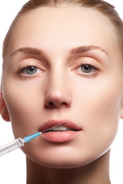Young woman with clean fresh skin close-up. Beautiful woman face close up studio on white. Beautiful woman gets injection in her facr. Isolated on white background. Beautiful face and the syringe