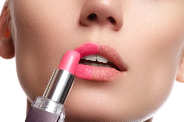 Close up portrait of attractive lips of beautiful woman. Rouging her lips with pink mate lipstick. The lady is gently smiling. Close-up of woman applying pink lipstick on her lips — Zdjęcie stockowe