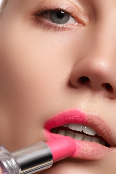 Primer plano retrato de labios atractivos de mujer hermosa. Enrojeciendo sus labios con lápiz labial rosa mate. La señora sonríe suavemente. Primer plano de la mujer que aplica lápiz labial rosa en sus labios —  Fotos de Stock