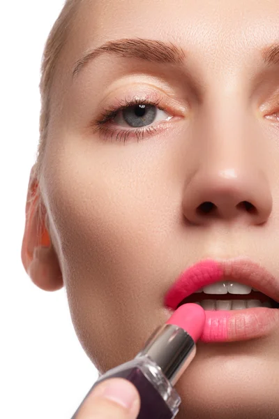 Close up portrait of attractive lips of beautiful woman. Rouging her lips with pink mate lipstick. The lady is gently smiling. Close-up of woman applying pink lipstick on her lips — Zdjęcie stockowe