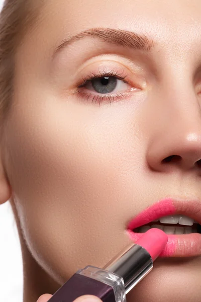 Close up portrait of attractive lips of beautiful woman. Rouging her lips with pink mate lipstick. The lady is gently smiling. Close-up of woman applying pink lipstick on her lips — 스톡 사진