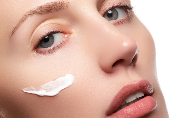 Bella giovane donna con pelle fresca pulita primo piano. Bella donna faccia da vicino studio su bianco. Giovane donna con crema cosmetica su un viso fresco e pulito. concetto di cura della pelle — Foto Stock