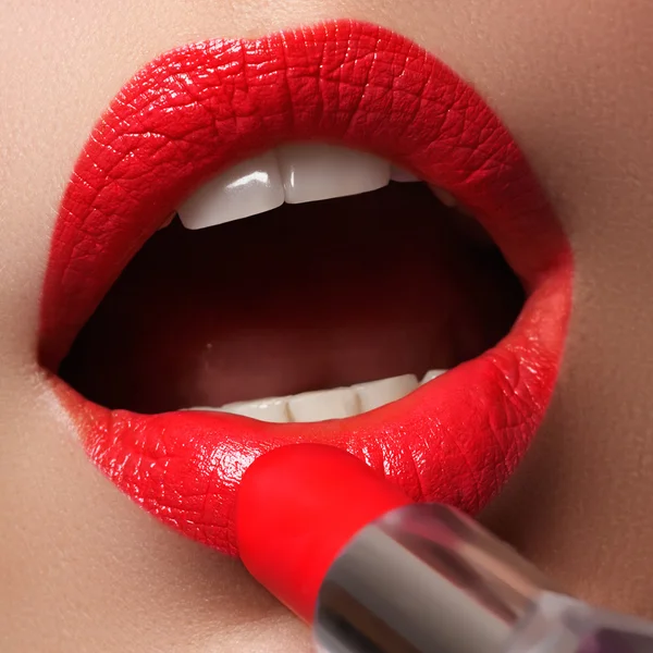 Extrême gros plan sur le modèle appliquant rouge à lèvres rouge. Maquillage. Maquillage professionnel rétro mode. Rouge à lèvres rouge . — Photo