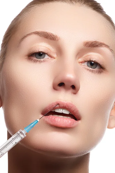 Young woman with clean fresh skin close-up. Beautiful woman face close up studio on white. Beautiful woman gets injection in her facr. Isolated on white background. Beautiful face and the syringe — Zdjęcie stockowe