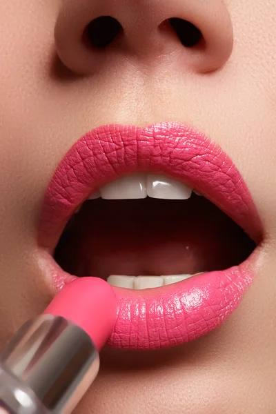 Woman painted pink lips. Beauty lips make-up. Perfect skin, full lips. Retro make up. Professional make-up artist applying sexy lips makeup. Fashion makeup