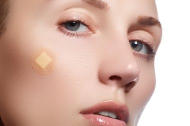 Close-up portrait of beautiful woman's purity face with natural make-up. Cute model with clean shiny skin. Beautiful young woman with clear-up patches or plaster on her skin. Skin care concept