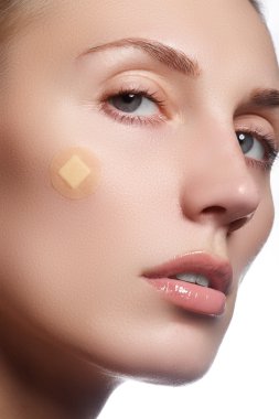 Close-up portrait of beautiful woman's purity face with natural make-up. Cute model with clean shiny skin. Beautiful young woman with clear-up patches or plaster on her skin. Skin care concept