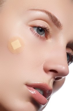 Close-up portrait of beautiful woman's purity face with natural make-up. Cute model with clean shiny skin. Beautiful young woman with clear-up patches or plaster on her skin. Skin care concept