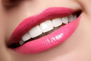 Macro happy woman's smile with healthy white teeth, bright pink .lips make-up. Stomatology and beauty care. Woman smiling with great teeth on white background. Cheerful female smile with fresh clear skin