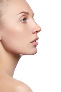 Temiz ciltli güzel bir yüz. Beyaz arka planda güzel mavi gözlü ve yüzü olan genç bir kadın portresi. Yakın plan, doğal makyajlı saf bir yüz. Temiz ciltli şirin bir model.