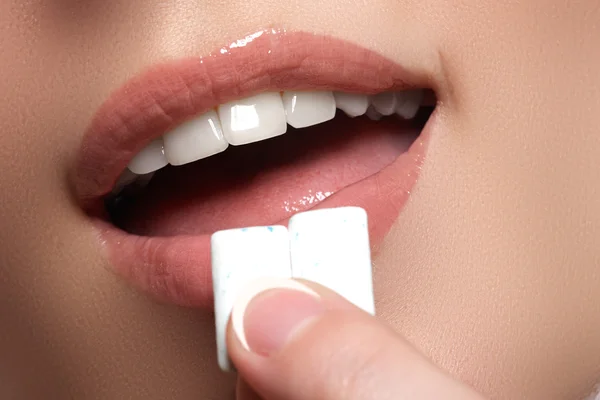 Closeup detail of woman putting pink chewing gum into her mouth. Chewing Gum, Eating, Women. Close up on a beautiful girl while enjoying a candy. — Stok fotoğraf