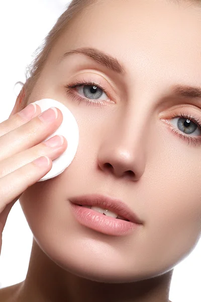 Portrait of a beautiful woman cleaning her face with cosmetic wad. Beautiful face of young adult woman with clean fresh skin. beautiful young woman cleaning skin by cotton pad, over white background. Cosmetics and healthcare — Stockfoto