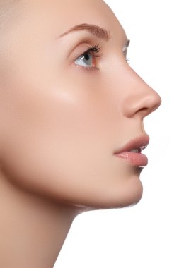 Temiz ciltli güzel bir yüz. Beyaz arka planda güzel mavi gözlü ve yüzü olan genç bir kadın portresi. Yakın plan, doğal makyajlı saf bir yüz. Temiz ciltli şirin bir model.