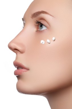 Güzel yüzünü bir yanağına kozmetik krem ile genç kadın. Cilt bakım kavramı. Portre portre üzerinde beyaz izole. Yakın çekim Genç güzel yüzünü uygulayarak kızın nemlendirici krem