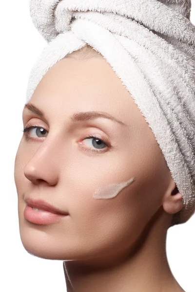 Güzel, sağlıklı bir kadının güzel portresi. Stüdyo, beyaz bir arka planda çekici bir kızı vurdu. Yüzünde bir fırçaya neden oldu. Yüzü soyulmuş. Kafasında havluyla güzel bir kız