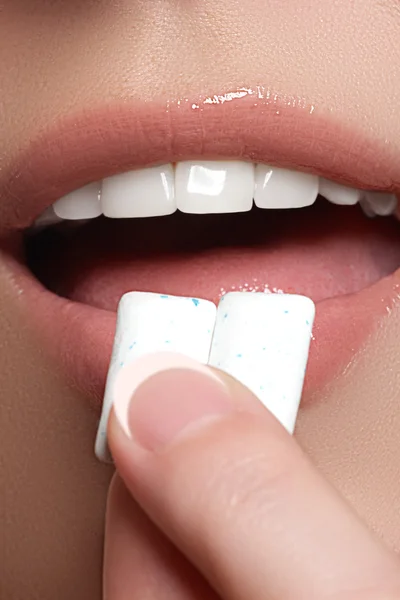 Closeup detail of woman putting pink chewing gum into her mouth. Chewing Gum, Eating, Women. Close up on a beautiful girl while enjoying a candy. — Stockfoto