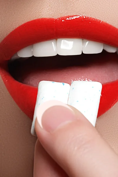 Closeup detail of woman putting chewing gum into her mouth. Chewing Gum, Eating, Women. Close up on a beautiful girl while enjoying a candy.Sexy red lips — Zdjęcie stockowe