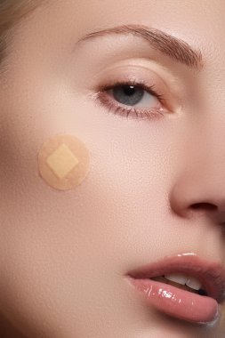 Close-up portrait of beautiful woman's purity face with natural make-up. Cute model with clean shiny skin. Beautiful young woman with clear-up patches or plaster on her skin. Skin care concept