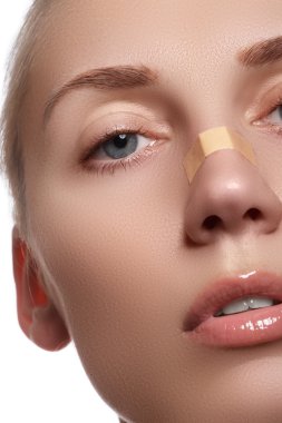 Close-up portrait of beautiful woman's purity face with natural make-up. Cute model with clean shiny skin. Beautiful young woman with clear-up patches or plaster on her skin. Skin care concept