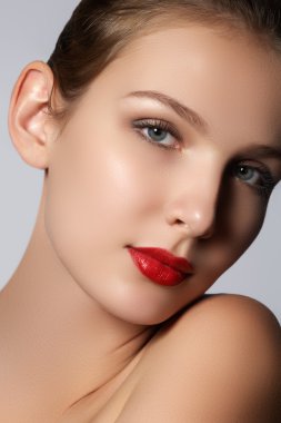 Beauty model girl with perfect make-up looking at camera isolated over white background. Portrait of attractive young woman with brown hair on white background. Beautiful female face with clear fresh skin. Model with red lips