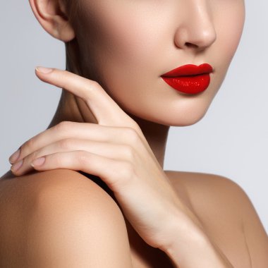 Beautiful young model with red lips and french manicure. Part of female face with red lips. Close-up shot of woman lips with glossy red lipstick. Glamour red lips make-up, purity skin. Retro beauty style