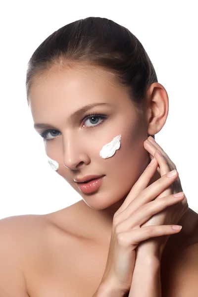 Cuidados com a pele senhora colocando creme facial. Menina morena atraente no fundo branco. Bela cara de mulher jovem com a nata cosmética em uma face. Conceito de cuidados com a pele. Produtos para a pele — Fotografia de Stock