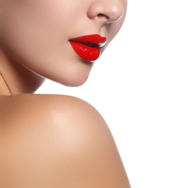 Close-up shot of woman lips with glossy red lipstick. Glamour red lips make-up, purity skin. Retro beauty style. Beautiful model girl with beauty makeup, red lips, perfect fresh skin. Youth and Skin Care Concept