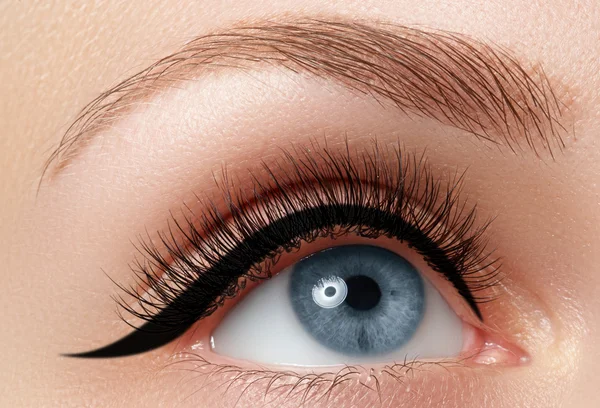 Elegance close-up of beautiful female eye with fashion eyeshadow and eyeliner. Macro shot of woman's beautiful blue eye with extremely long eyelashes. Sexy view, sensual look Royalty Free Stock Images