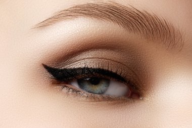 Cosmetics & make-up. Beautiful female eye with sexy black liner makeup. Fashion big arrow shape on woman's eyelid. Chic evening make-up clipart