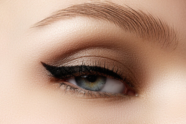 Cosmetics & make-up. Beautiful female eye with sexy black liner makeup. Fashion big arrow shape on woman's eyelid. Chic evening make-up