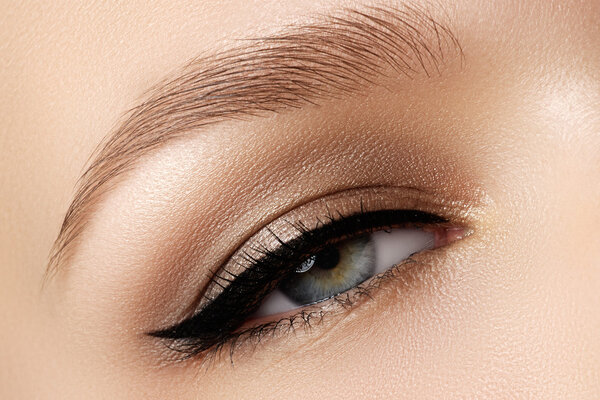 Cosmetics & make-up. Beautiful female eye with sexy black liner makeup. Fashion big arrow shape on woman's eyelid. Chic evening make-up