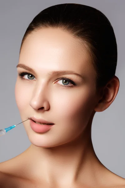 Nahaufnahme der schönen Frau bekommt Injektion in ihre Lippen. volle Lippen. schönes Gesicht und die Spritze (plastische Chirurgie und kosmetisches Injektionskonzept)). — Stockfoto